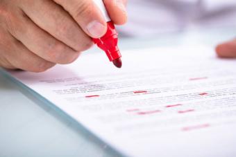 Close-up image of someone reading a document with a red marker in hand