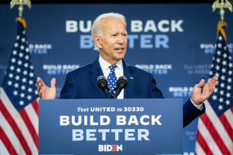 President Biden standing at a podium reading &quot;Build Back Better&quot; with a &quot;Build Back Better&quot; backdrop behind him