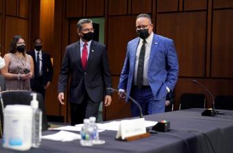 Secretary of Health Xavier Becerra and Secretary of Education Miguel Cardona wearing masks walking into hearing room