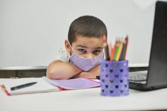 Young boy with mask at computer/desk